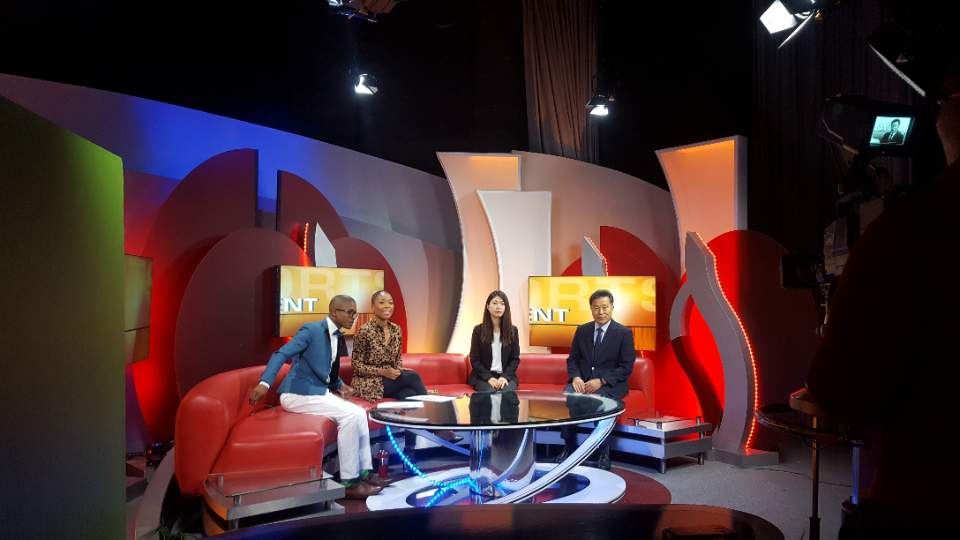A guest speaker on a TV studio sofa during a live interview.
