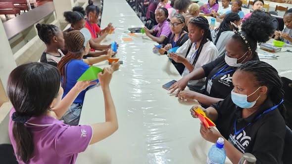 Young people making crafts at a long table.
